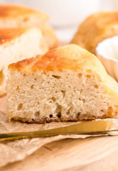 Close up photo of a slice of Bannock bread on a piece of parchment on a wooden cutting board.