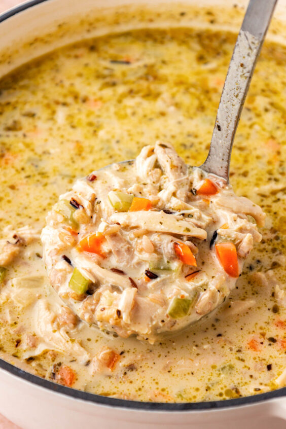 Close up of a ladle of chicken and wild rice soup coming out of the pot.