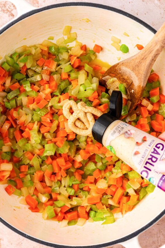 Garlic paste being added to mise en place in a pot.