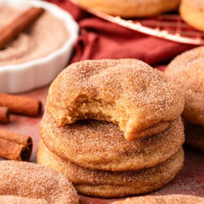 A stack of three Snickerdoodle cookies on a table, the top one is missing a bite.