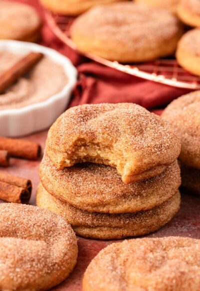 A stack of three Snickerdoodle cookies on a table, the top one is missing a bite.