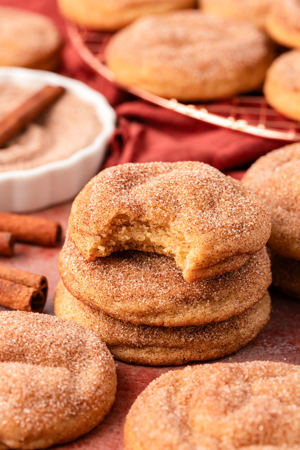 A stack of three Snickerdoodle cookies on a table, the top one is missing a bite.