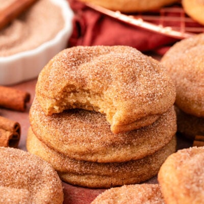 A stack of three Snickerdoodle cookies on a table, the top one is missing a bite.