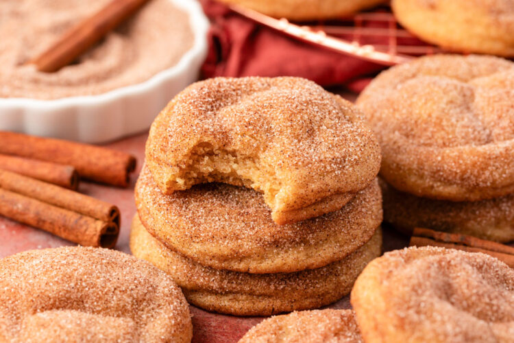 A stack of three Snickerdoodle cookies on a table, the top one is missing a bite.