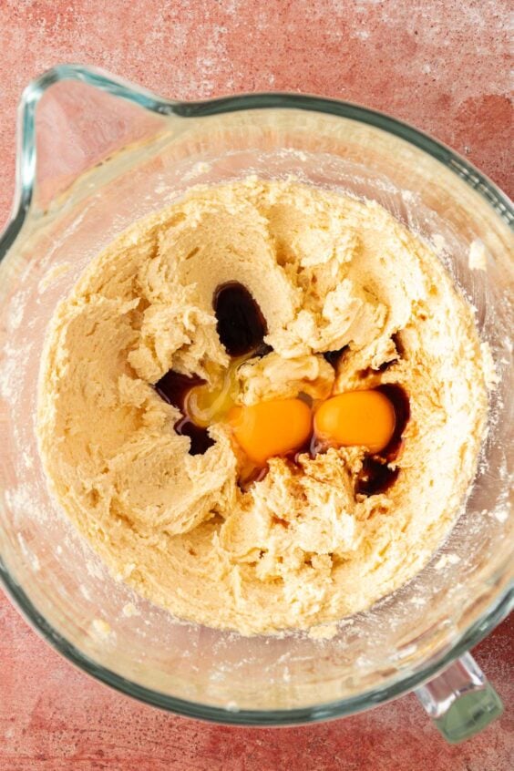 Egg being added to cookie dough being prepped in a bowl.