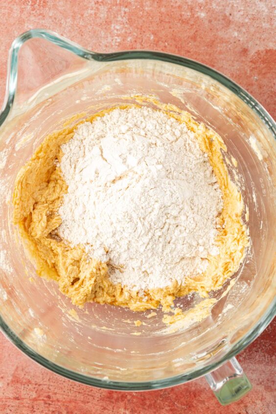 Flour being added to cookie dough in a bowl.