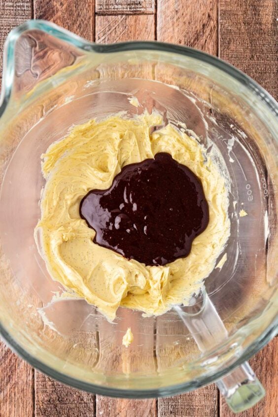 Melted chocolate being added to butter in a mixing bowl.