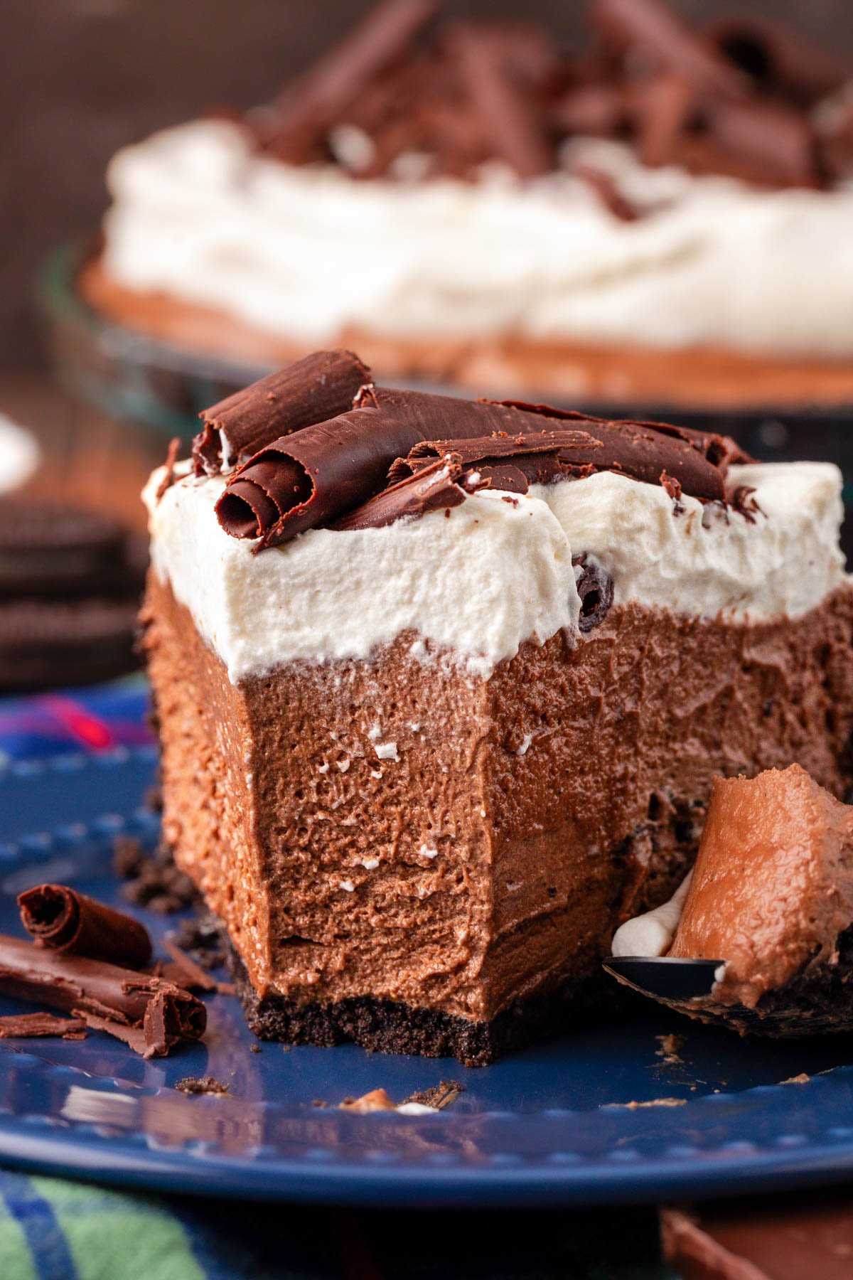 Close up of a slice of chocolate silk pie on a blue plate missing a bite.