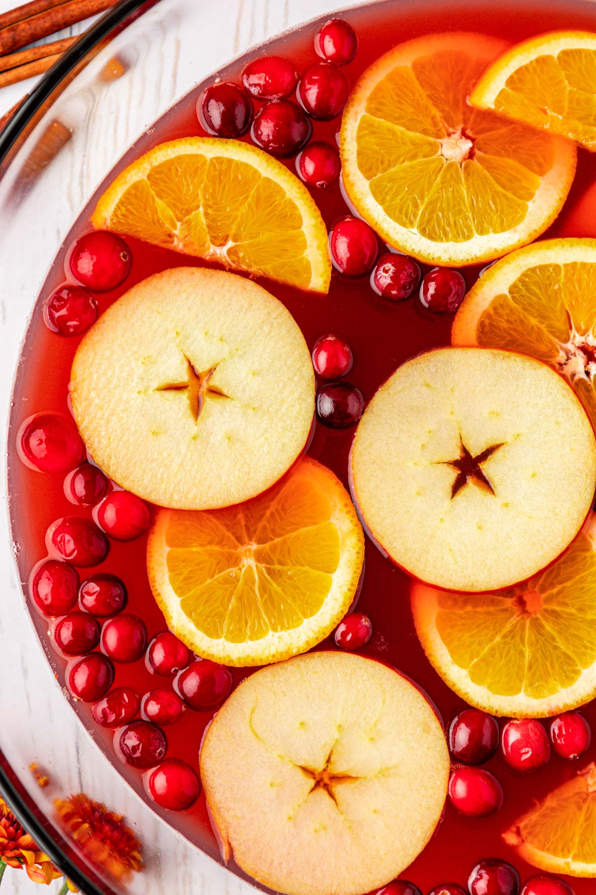 Overhead photo of a bowl of red party punch garnished with apple and orange slices and cranberries.