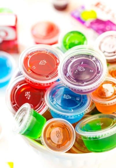 Multi colored jello shots in a white bowl.