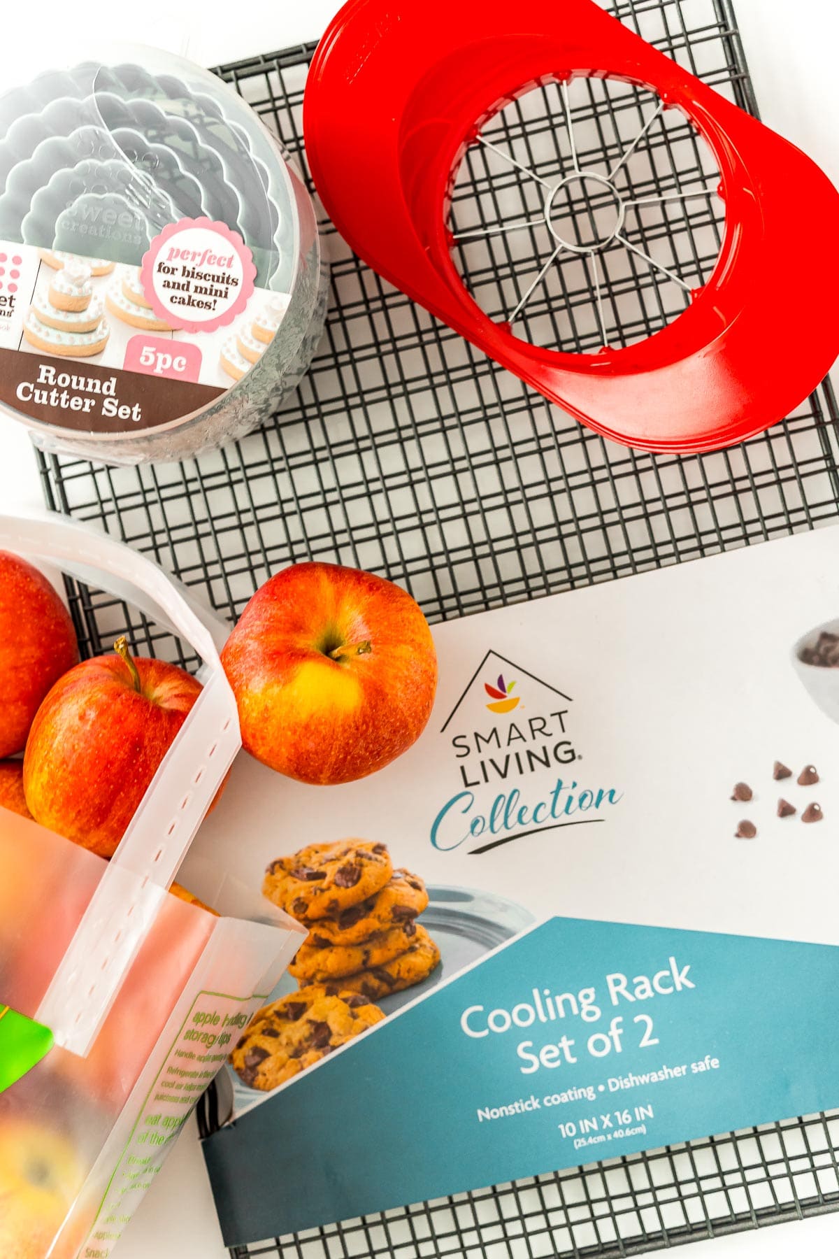 Overhead photo of a bag of apples, an apple corer, wire cooling racks, and biscuit cutters. 