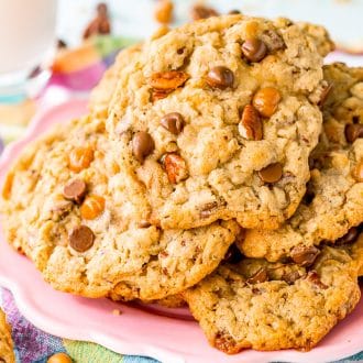 Horizontal photo of cowboy cookies tacked on a pink plate with a glass of milk in the background.