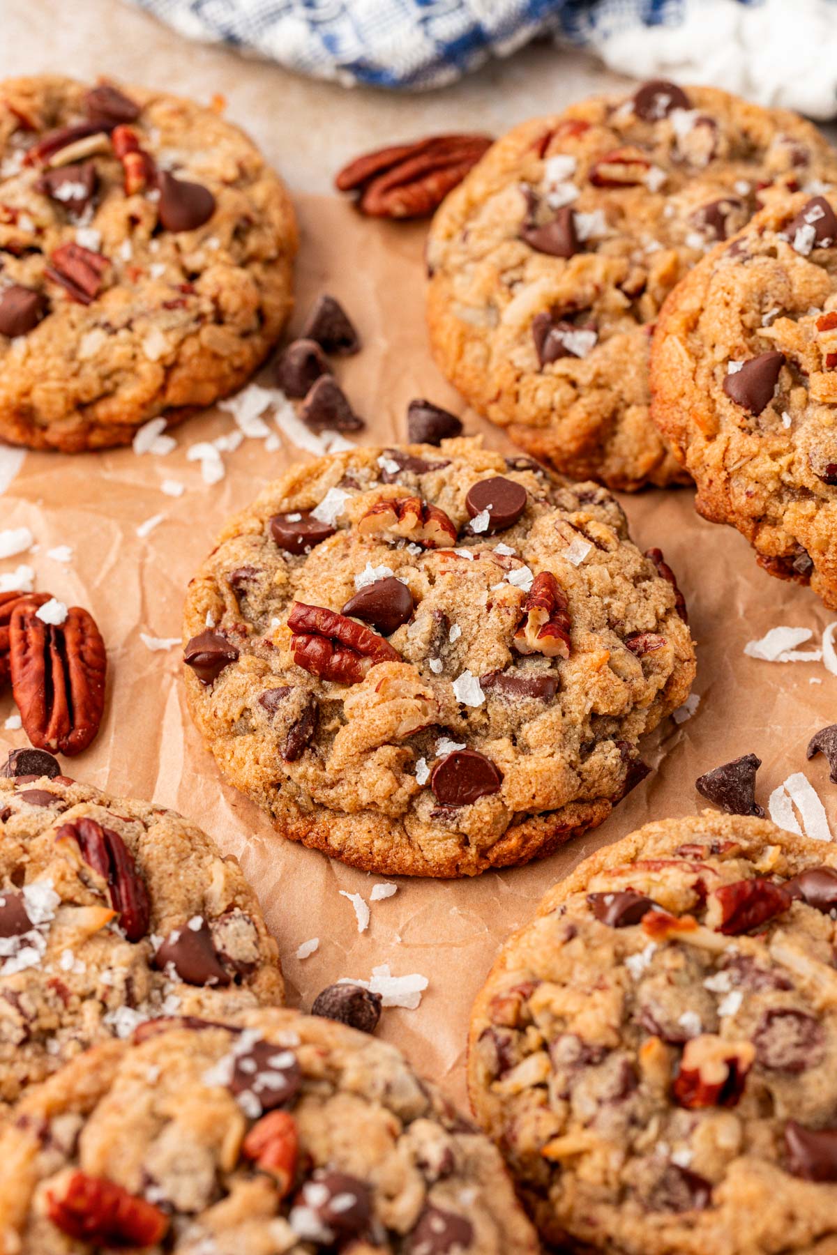 Close up of pecan, coconut, chocolate chip oatmeal cookies on a piece of parchment paper.