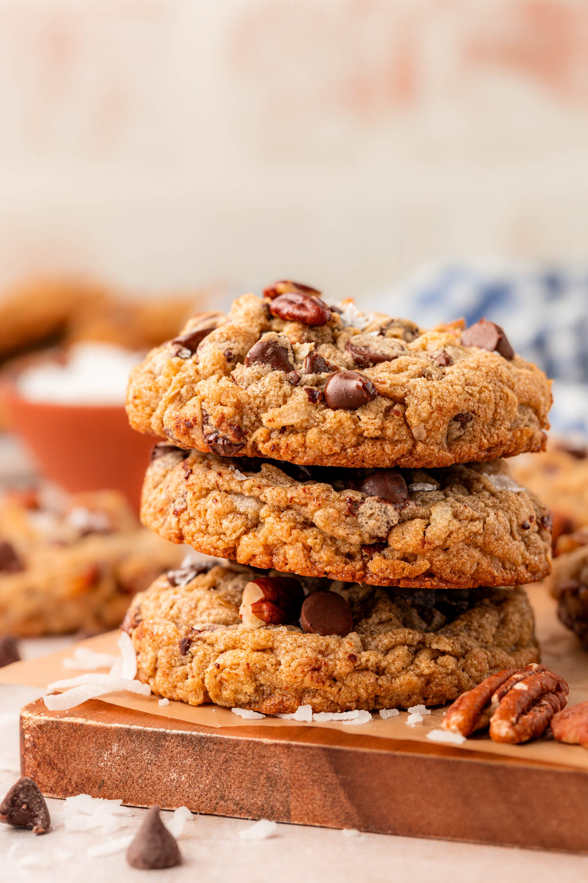 Stack of three cowboy cookies on a wooden cutting board.