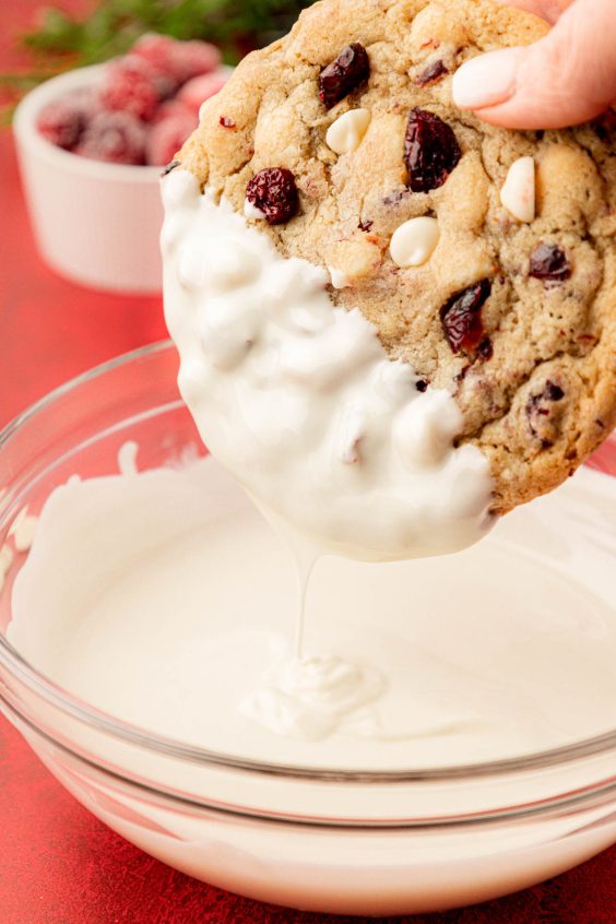 A cookie being dipped in white chocolate.