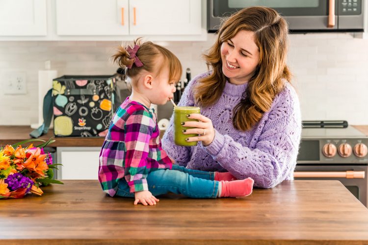 Mother and daughter in a kitchen drinking a smoothie.