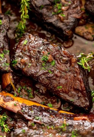 Braised beef short ribs in a pan with sauce.