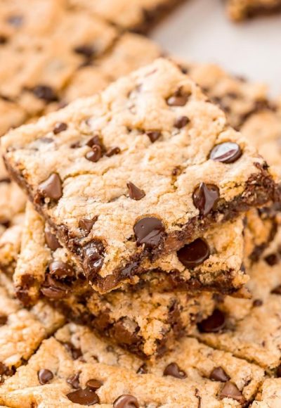 Stack of chocolate chip cookie squares on top of a pan.