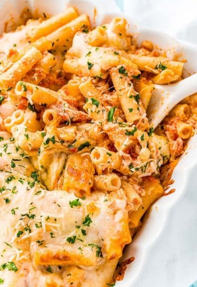 Baked ziti in a white casserole dish with a white serving spoon.