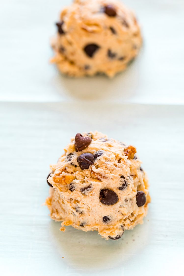 Cookie dough scoops on parchment paper on a baking sheet.