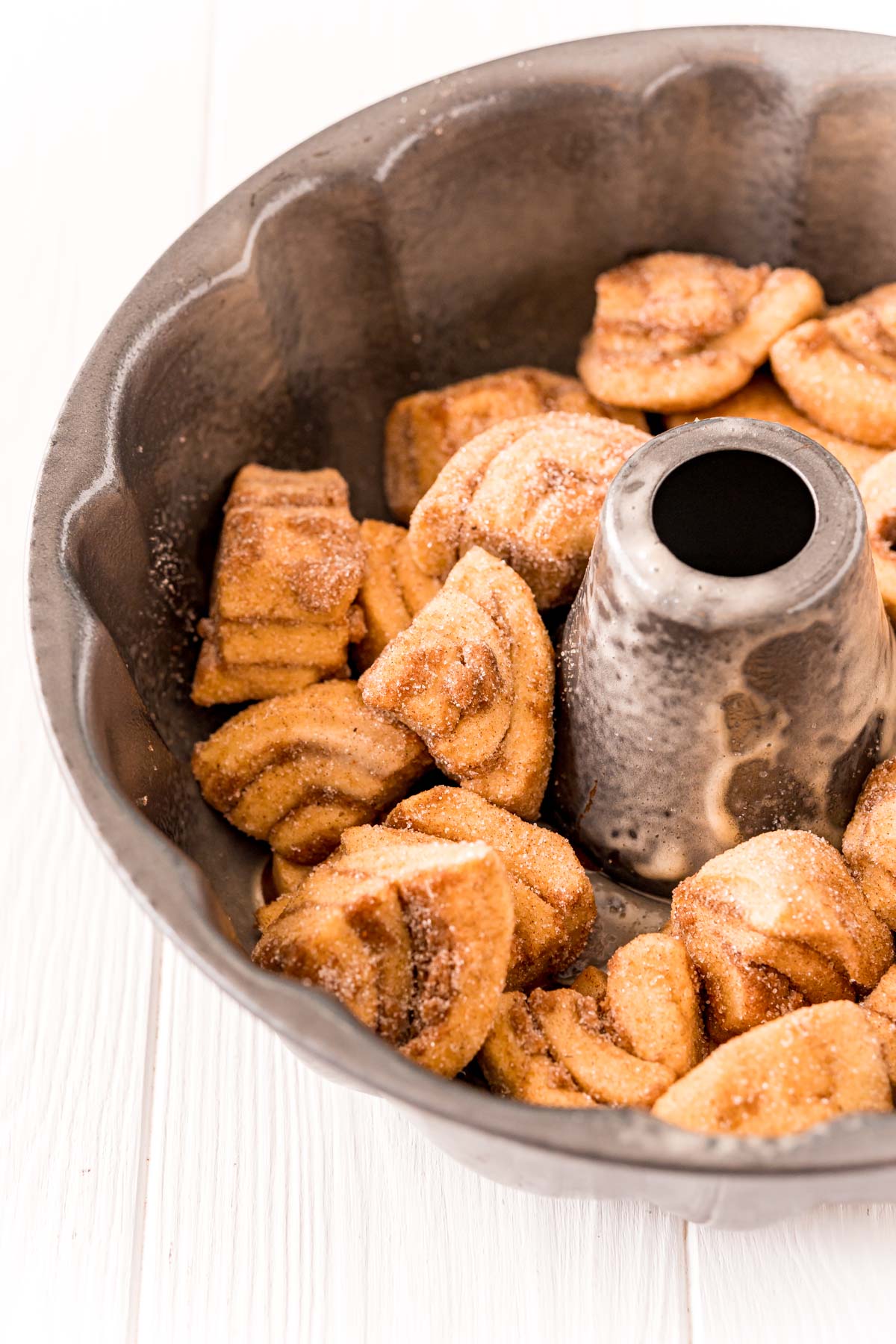 Quartered cinnamon rolls coated in cinnamon sugar in a bundt pan to make monkey bread.