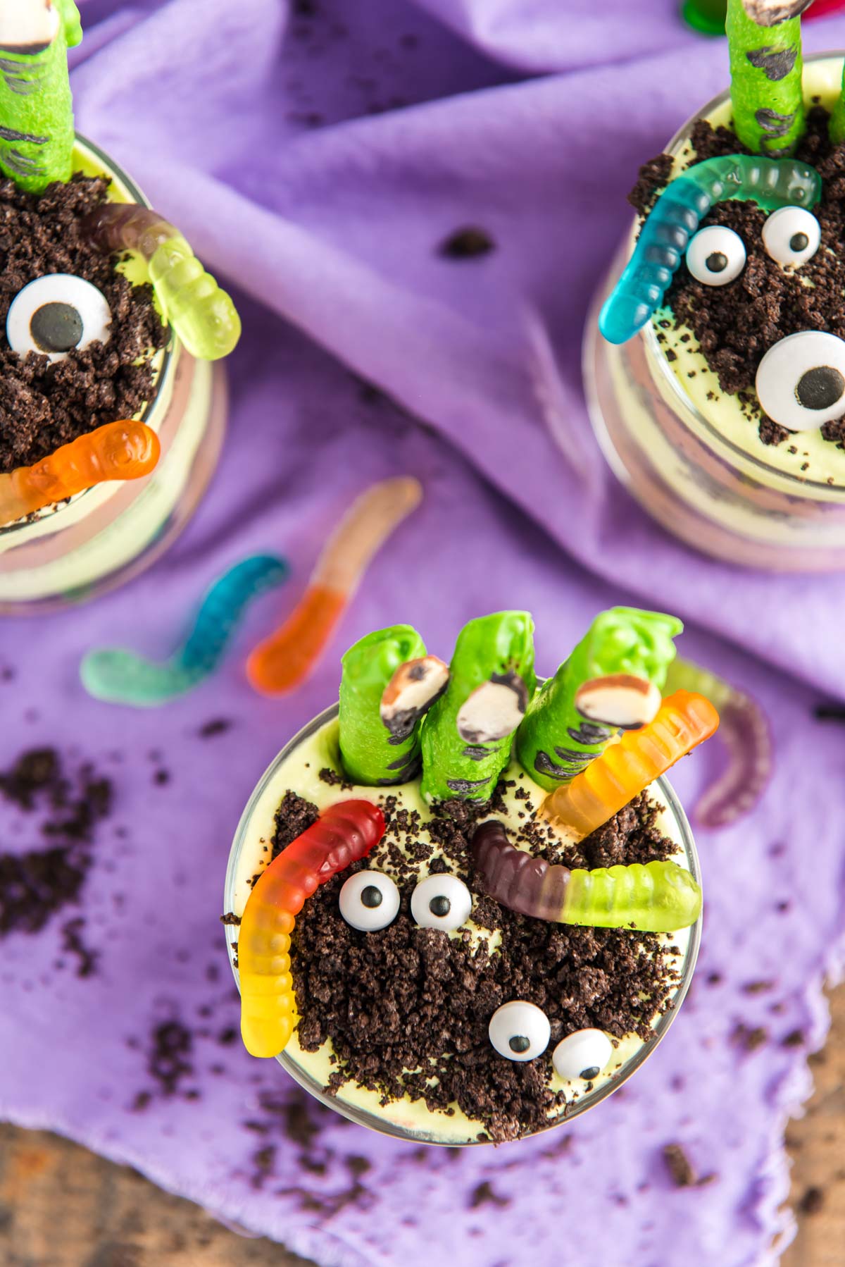 Close up photo of layers Halloween dirt cups with pretzel stick witch fingers, candy eyes, and gummy worms.