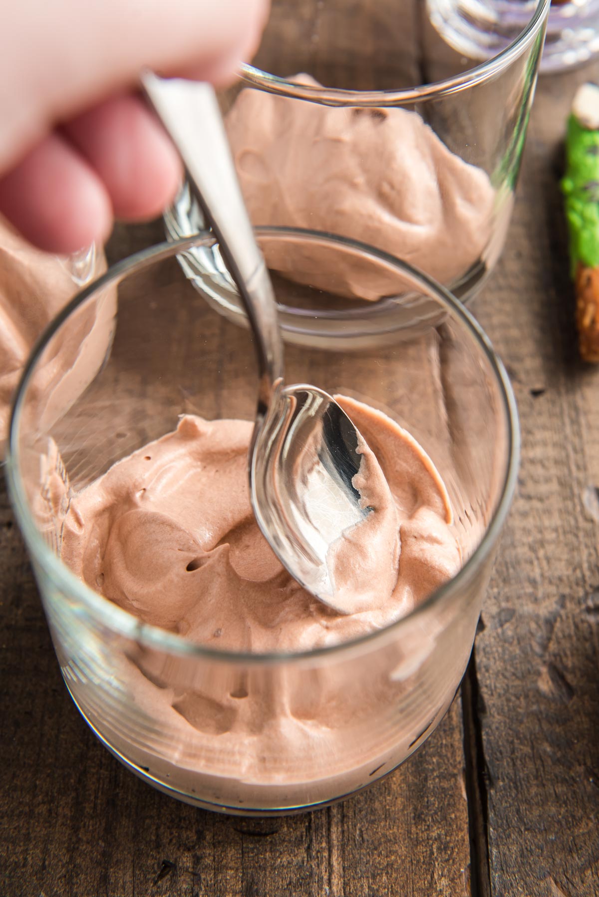 Chocolate cream cheese pudding being added to a small dessert cup.