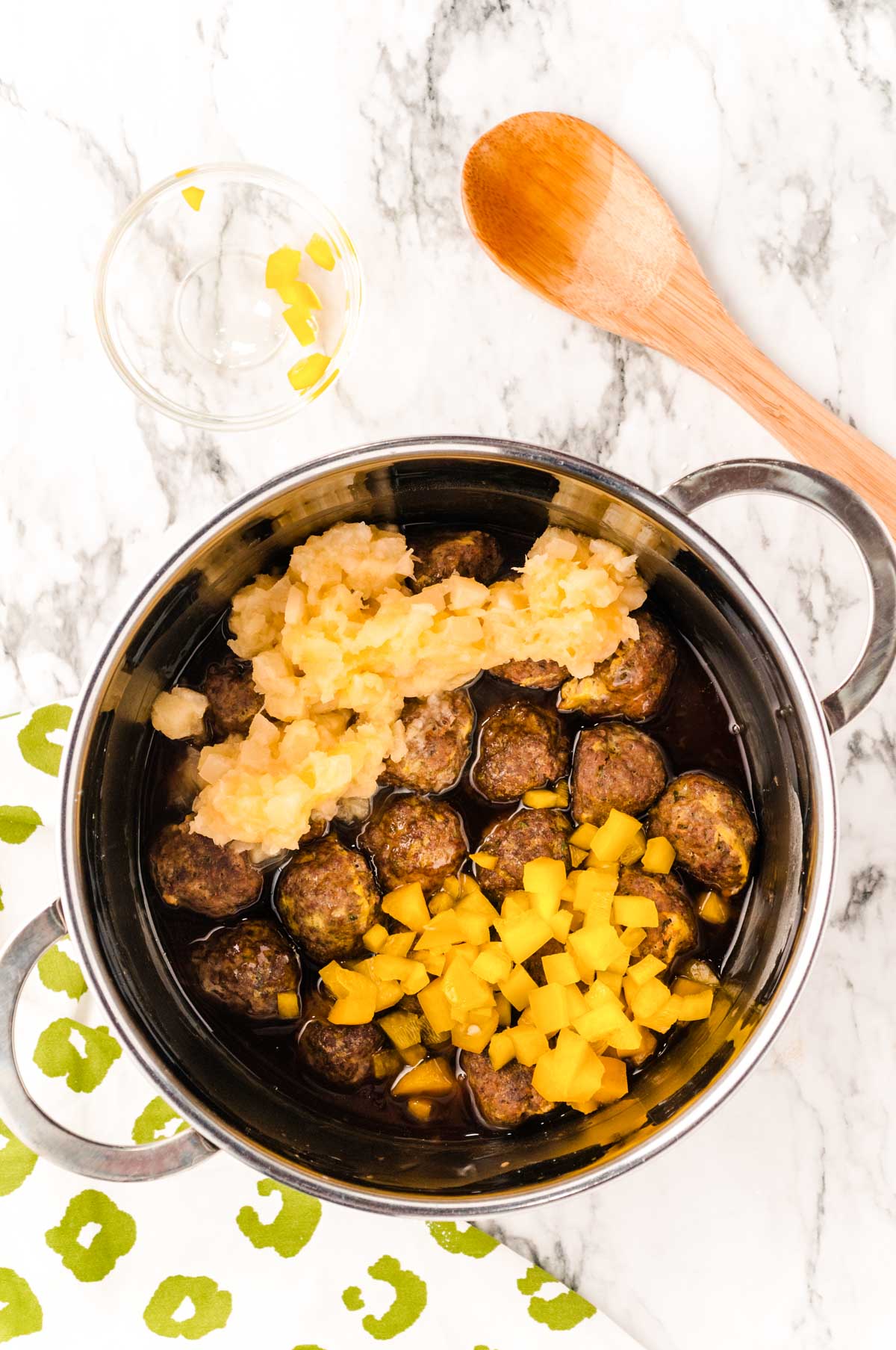 sweet and sour meatballs being made in a saucepan.