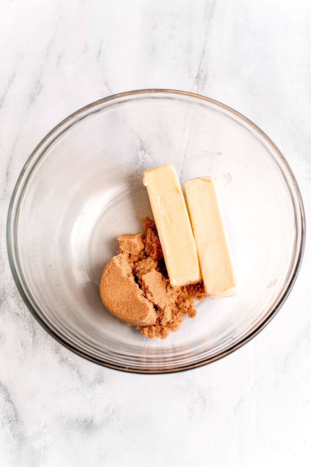 Overhead photo of butter and brown sugar in a glass mixing bowl.