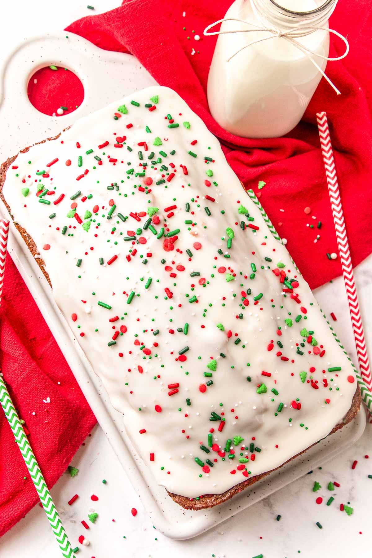 A loaf of quick bread with christmas sprinkles on a white serving tray.