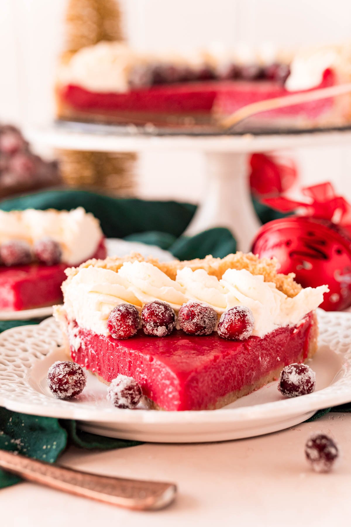 A slice of cranberry pie on a white plate with sugared cranberries.