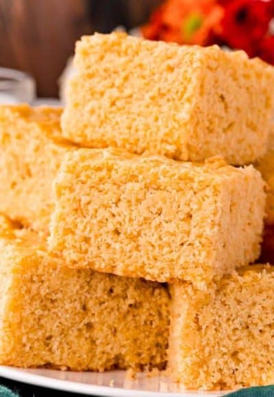 Close up photo of corn bread slices stacked on top of each other on a white plate.