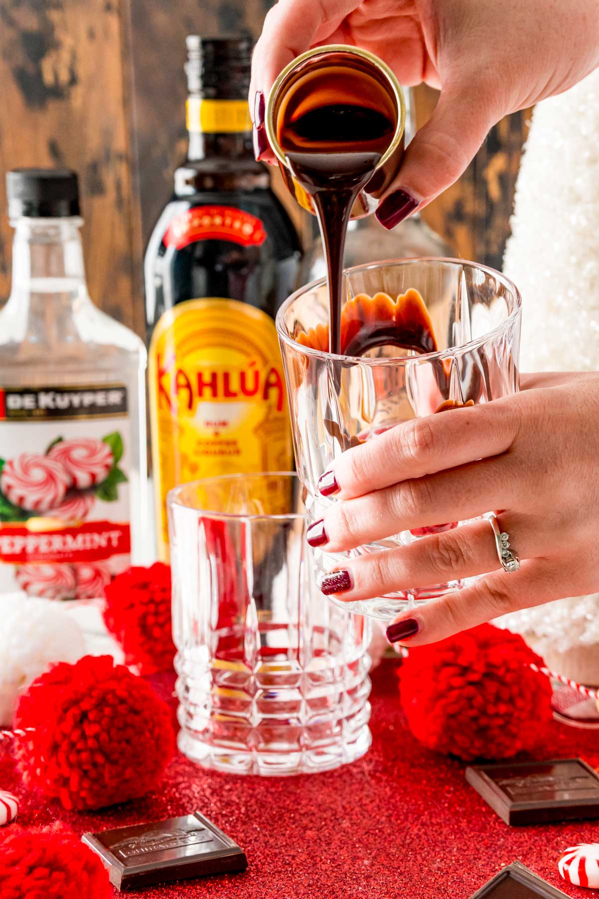 A woman's hand drizzling chocolate inside a rocks glass.