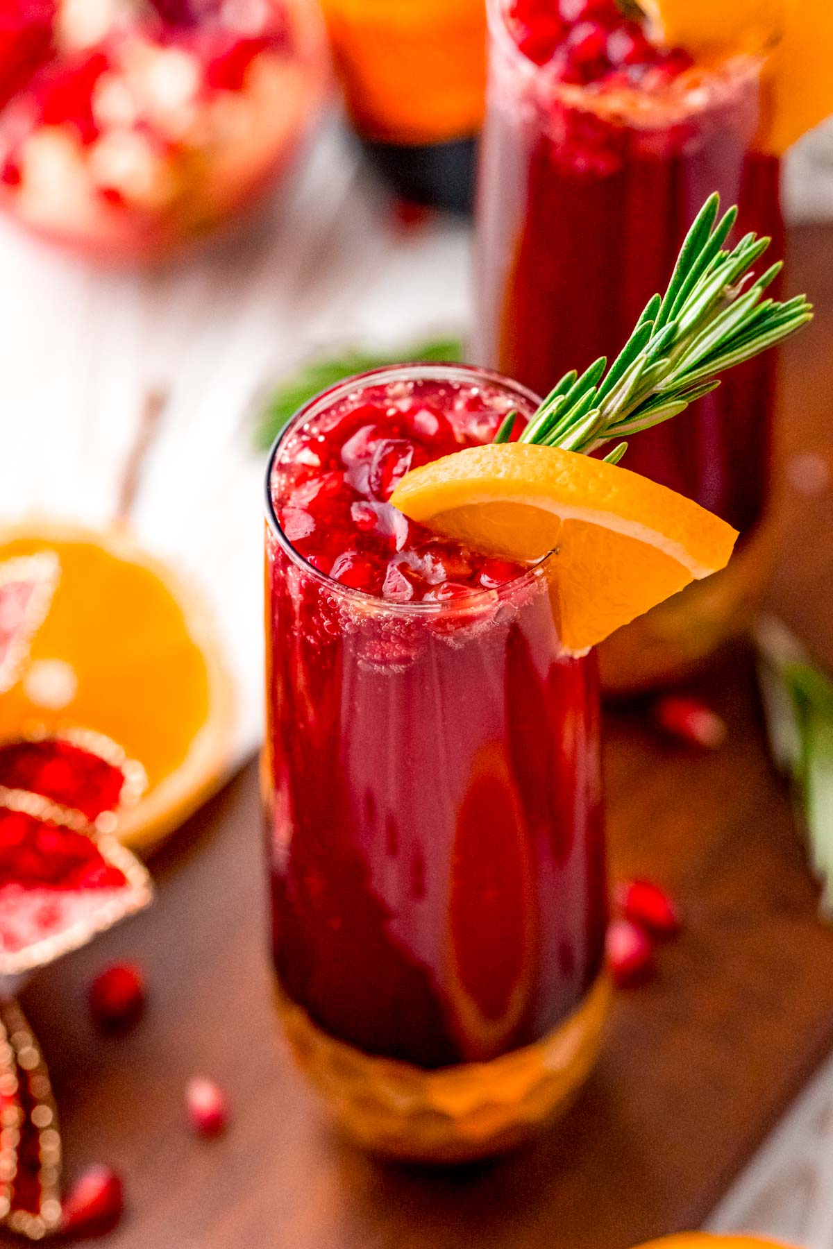 Close up photo of a pomegranate mimosa with orange and rosemary garnish.