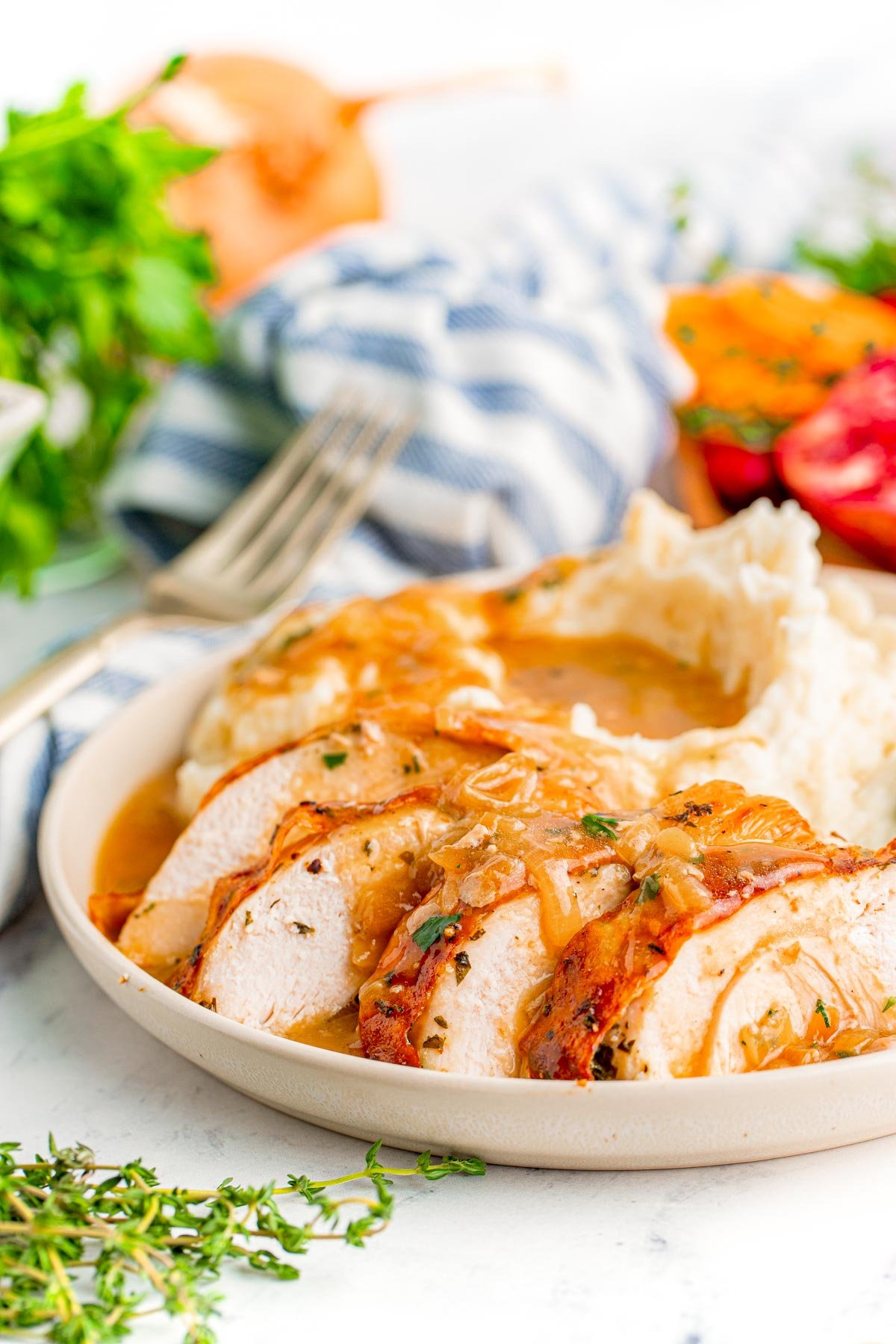 Sliced turkey breast on a white plate with mashed potatoes and gravy.