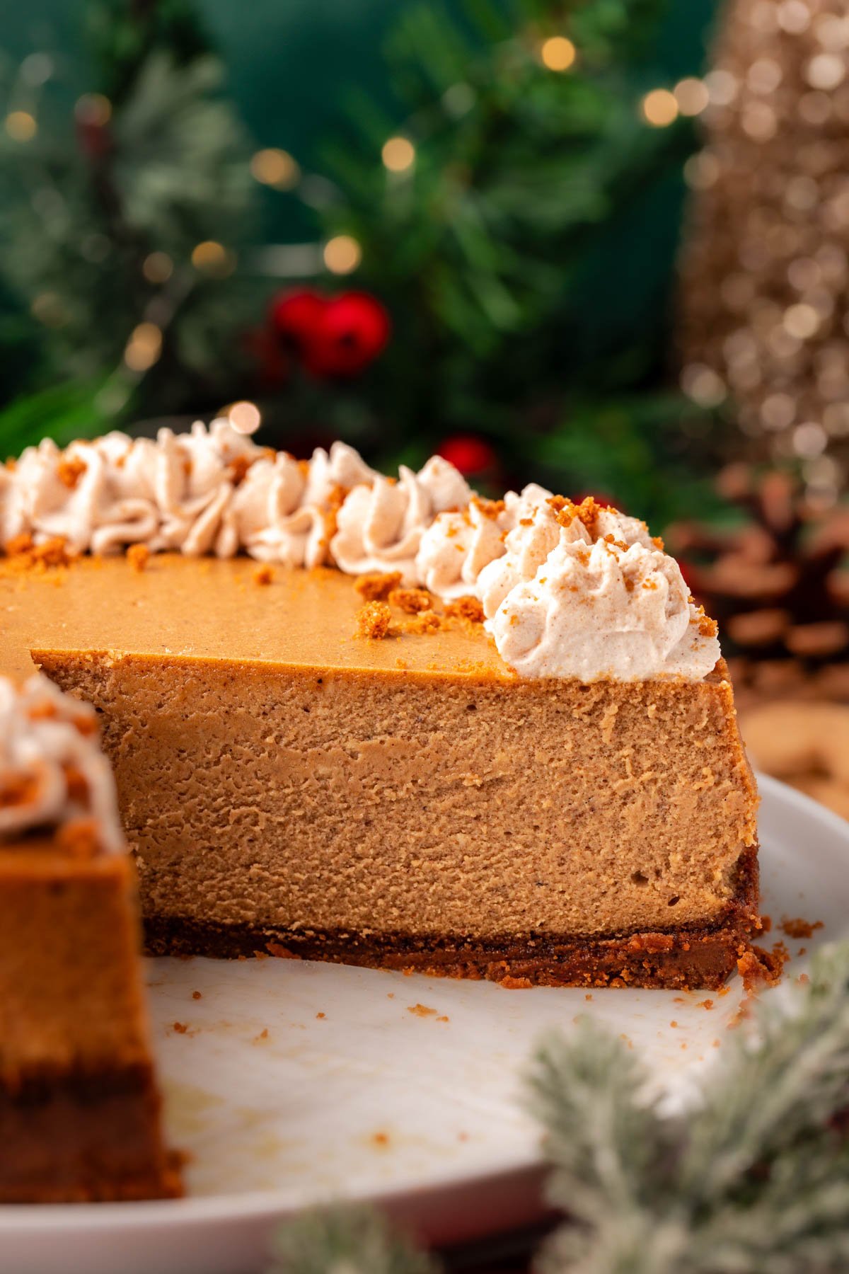 A gingerbread cheesecake on a cake stand with a slice removed.