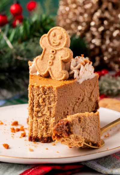 A slice of gingerbread cheesecake on a white plate with a bite taken out.