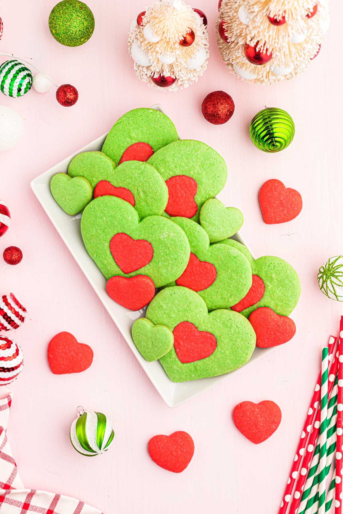 Heart-shaped Grinch cookies on a white plate.