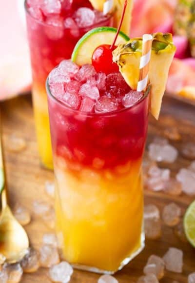 Close up photo of a Malibu Bay Breeze drink garnished with pineapple, cherry, and lime.