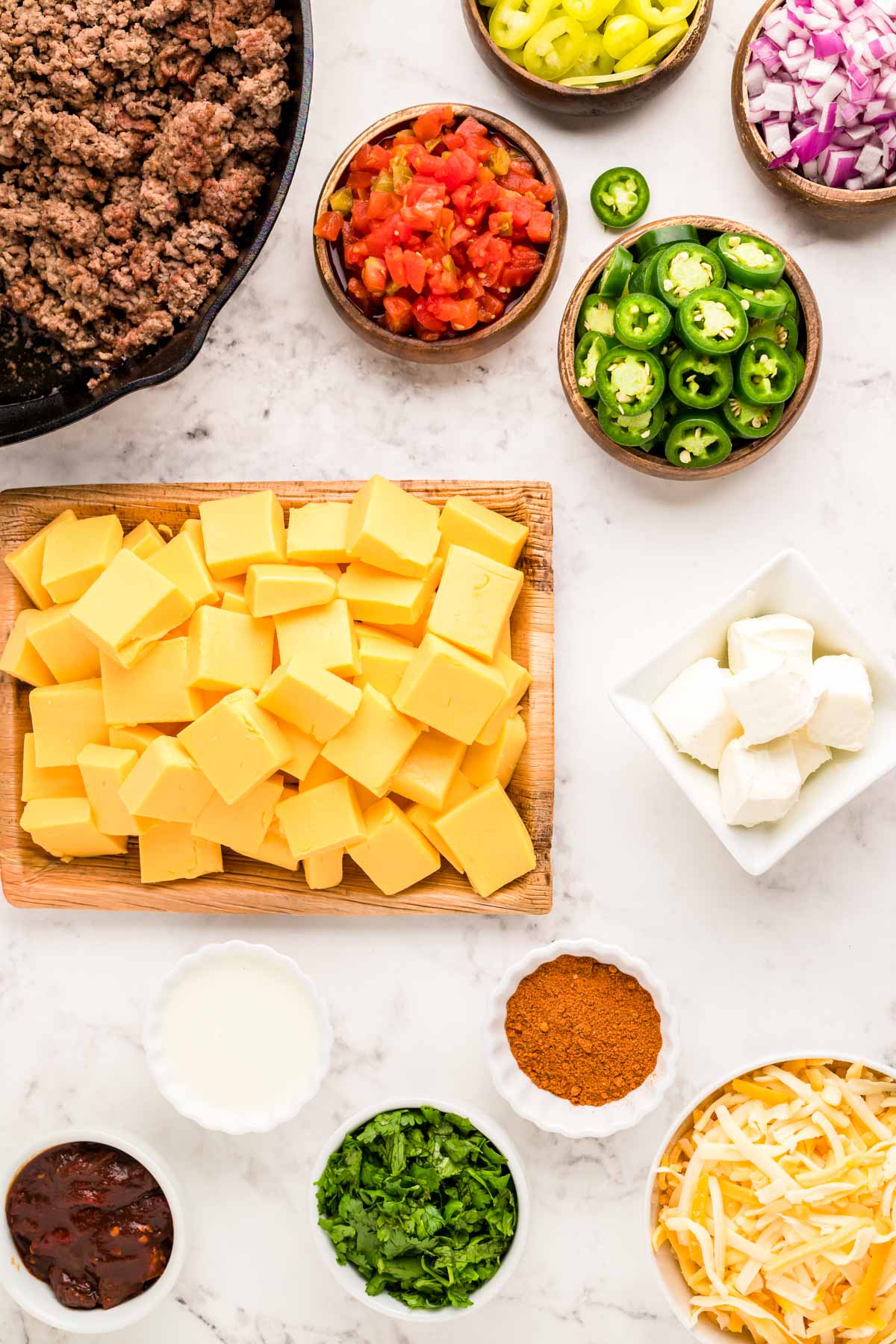 Overhead photo of ingredients to make smoked queso dip on a marble counter.