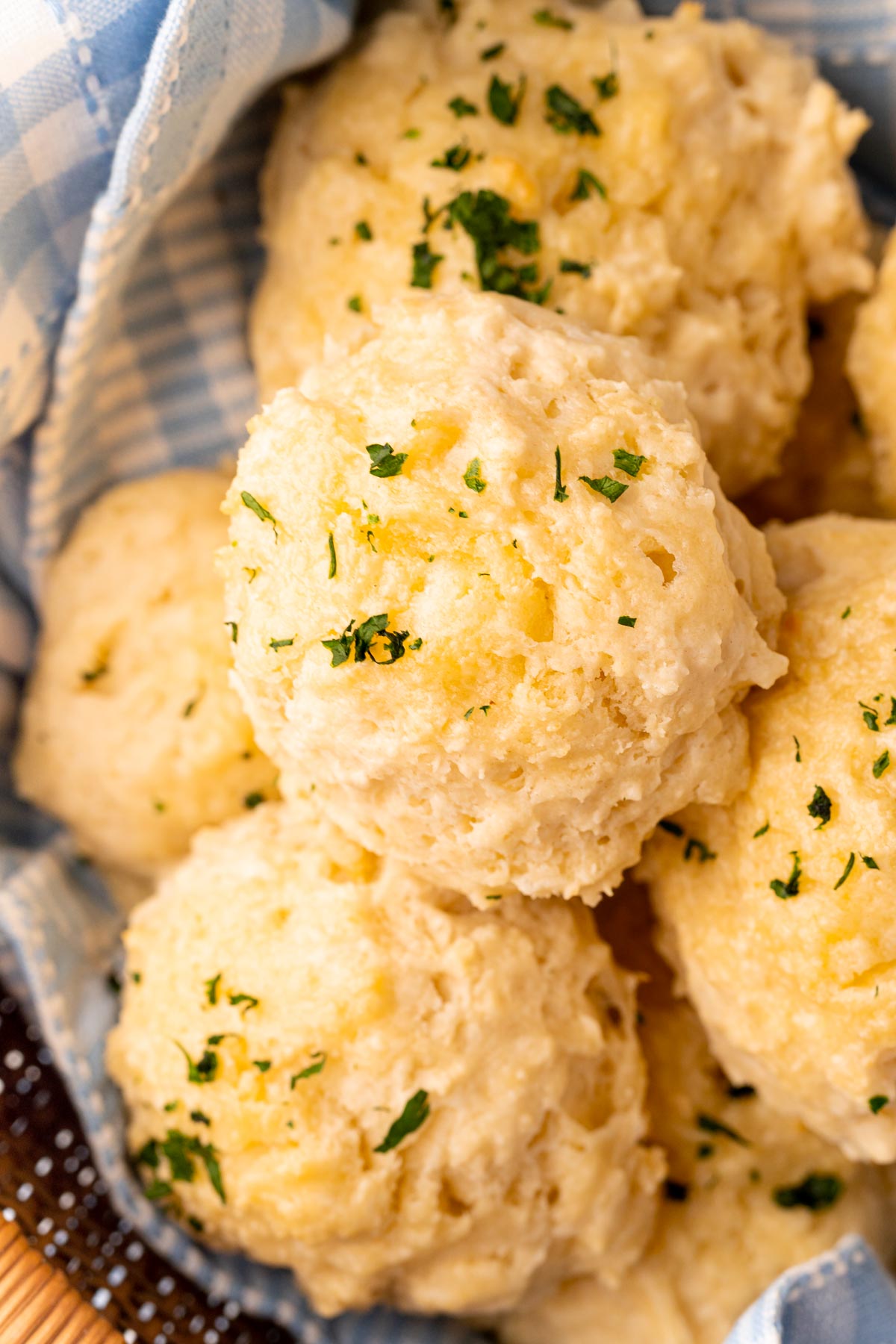 Close up photo of classic drop biscuits in a basket with a blue linen napkin.