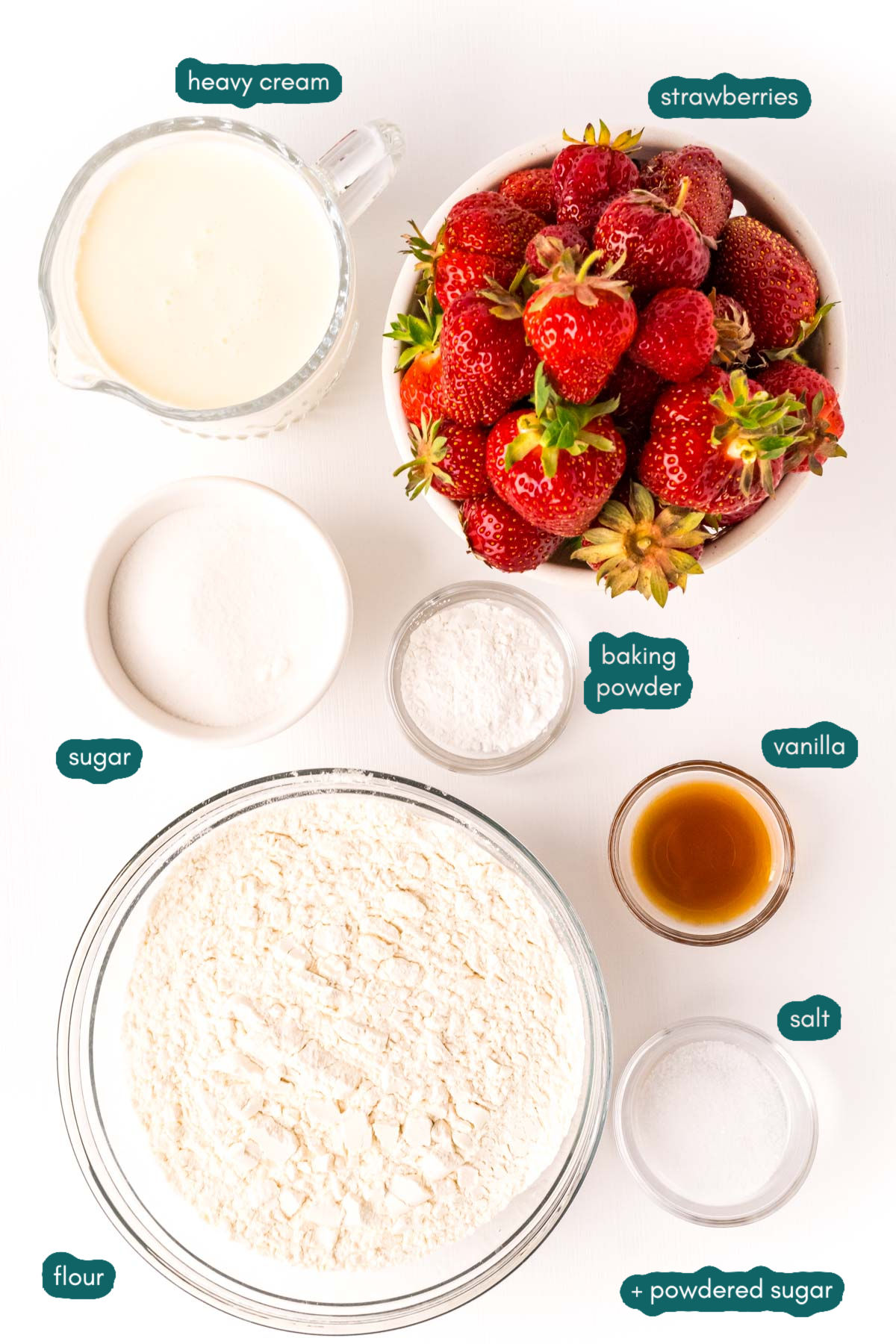 Overhead photo of ingredients to make strawberry shortcake prepped on a white table.