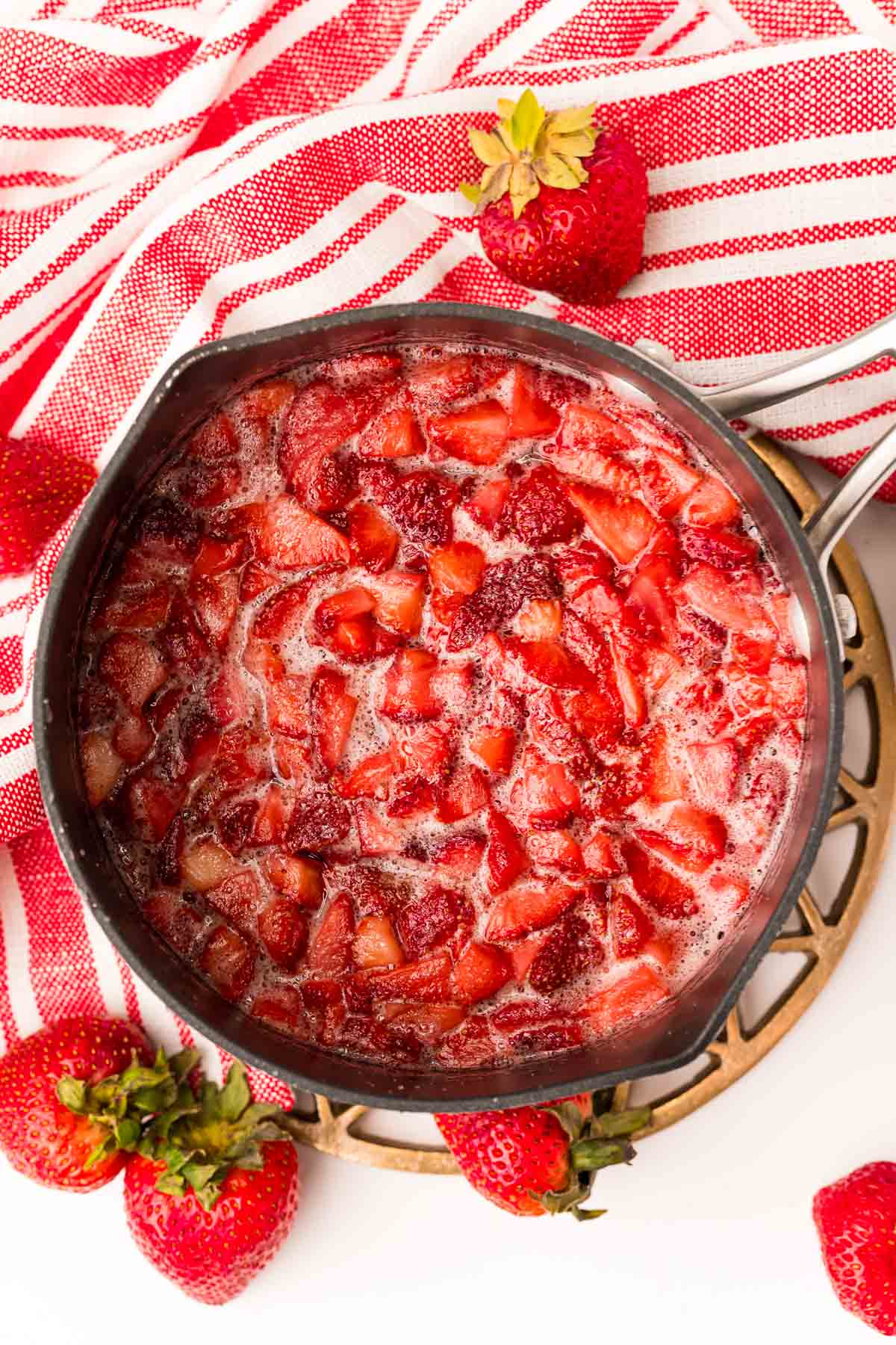 Overhead photo of a saucepan with strawberries in it to make strawberry simple syrup.