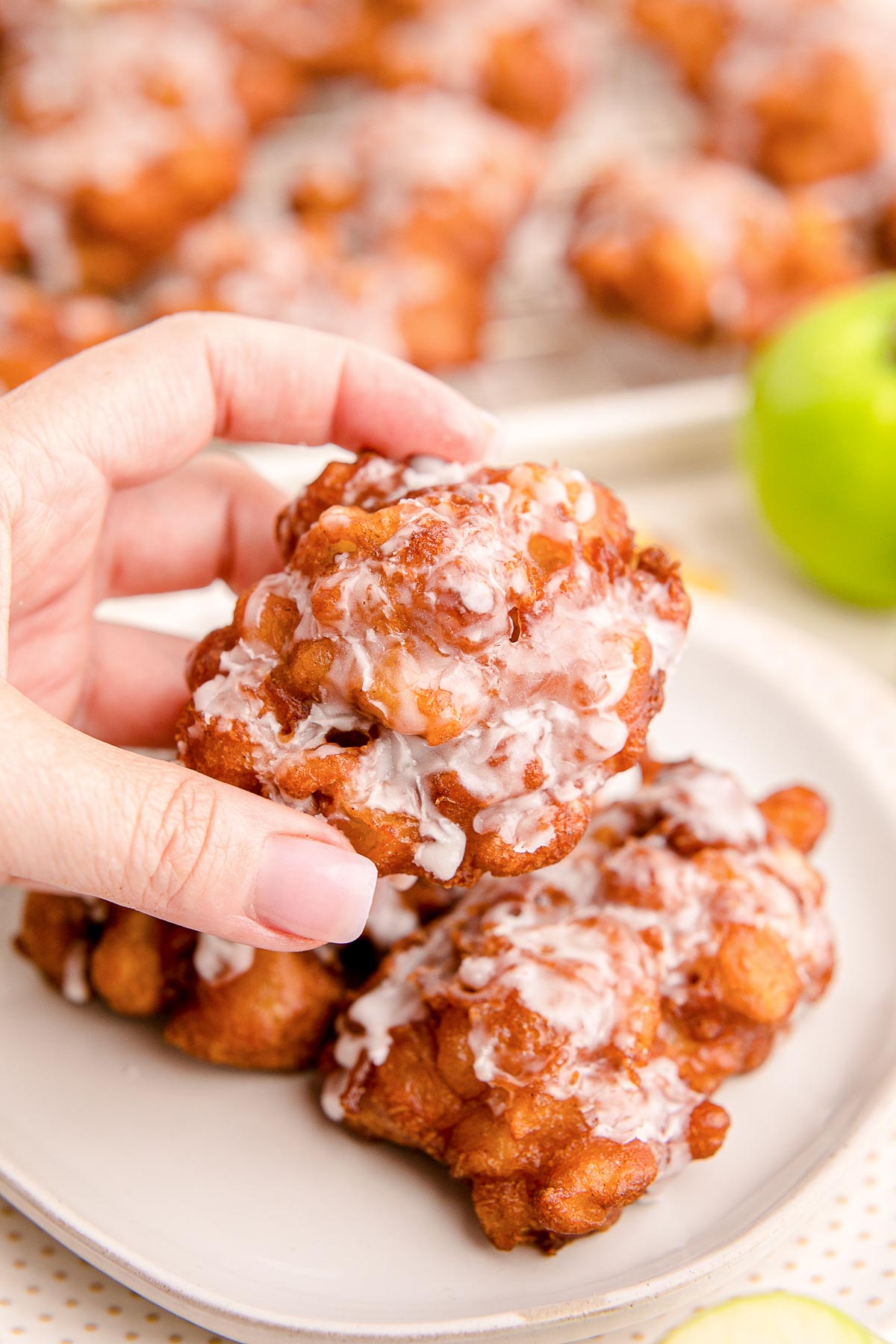 Close up photo of a woman's hand holding an apple fritter.