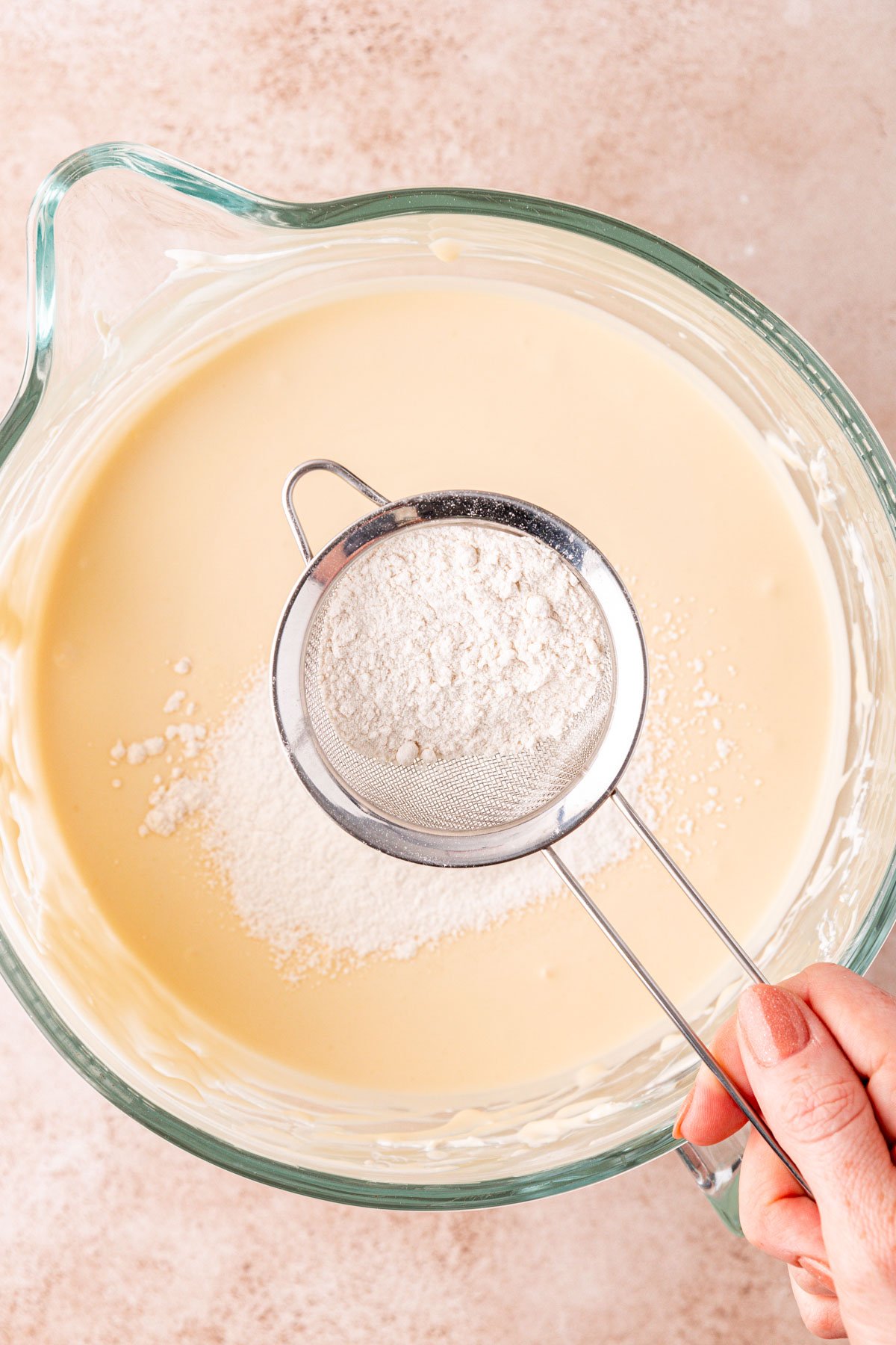 Flour being sifted into cheesecake mixture.