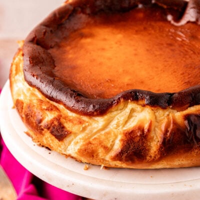 Close up of a whole basque cheesecake on a cake stand.