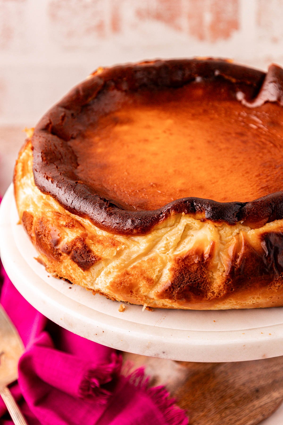 Close up of a whole basque cheesecake on a cake stand.