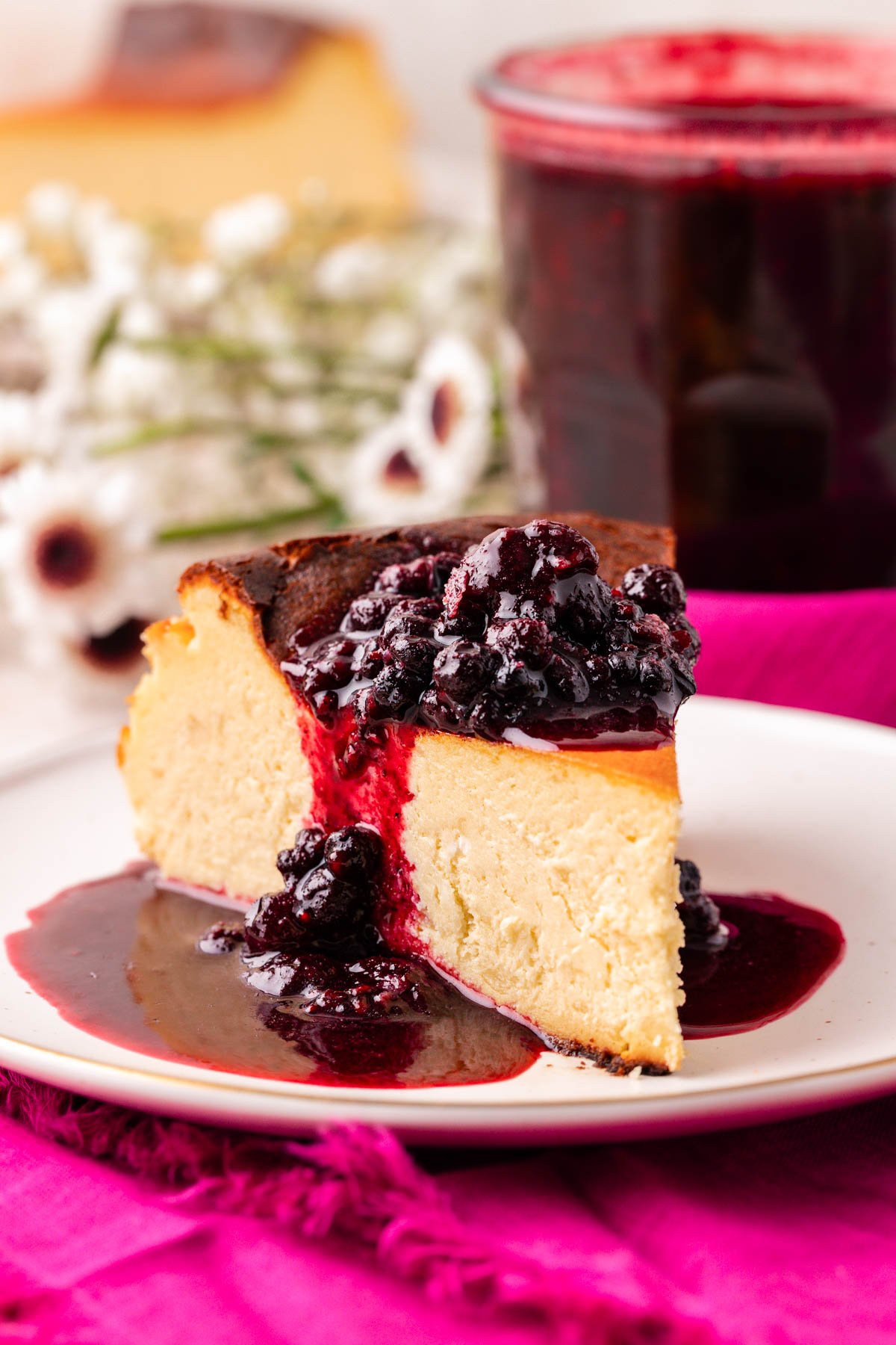 A slice of basque cheesecake with berry compote on it.