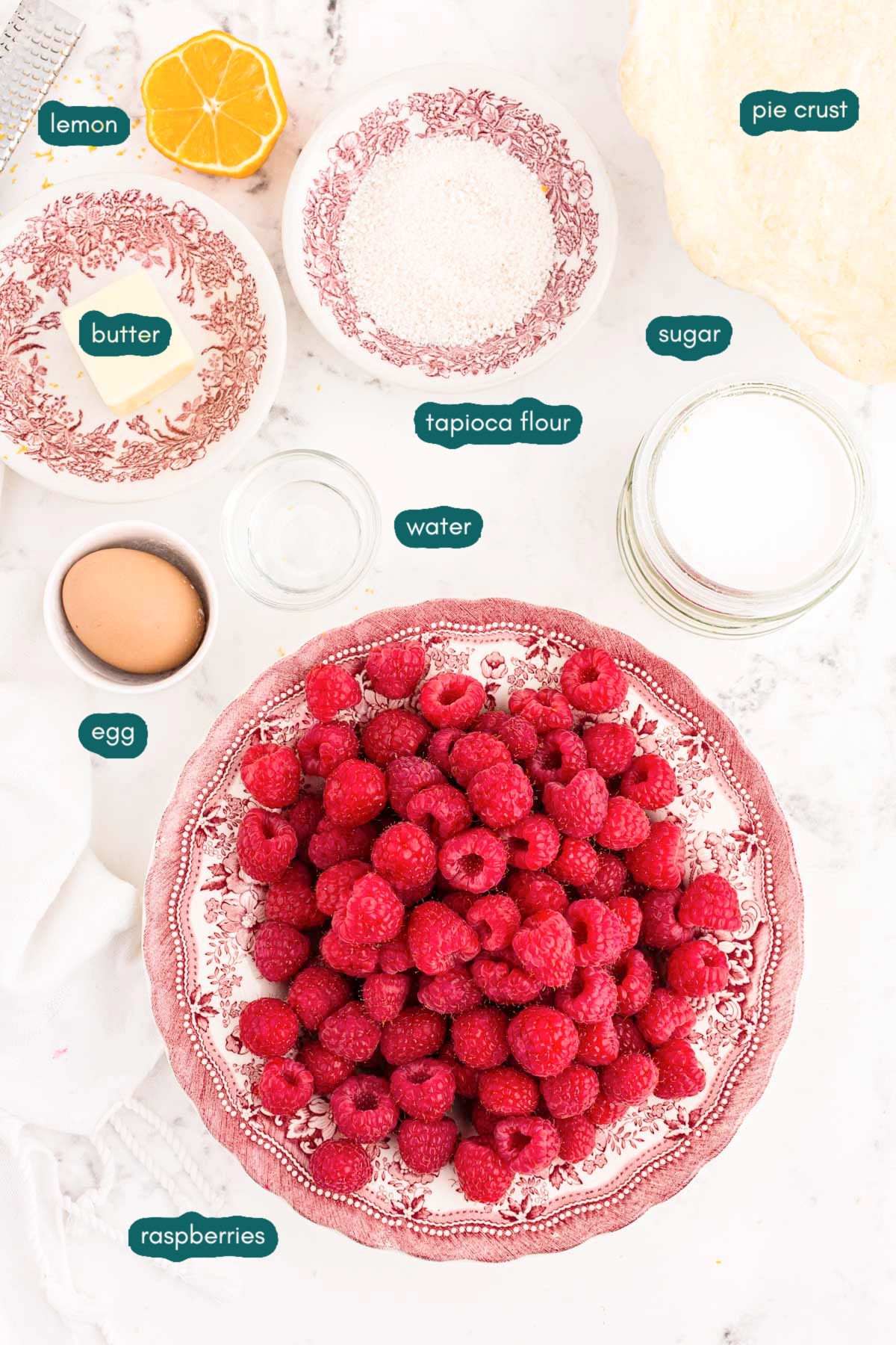 Ingredients for raspberry pie prepared on a white counter.