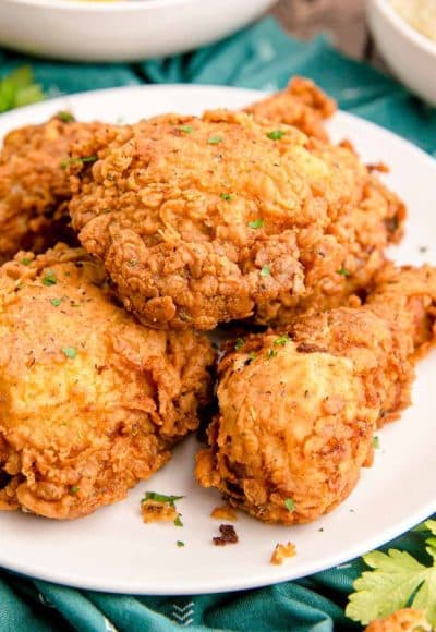 Close up photo of buttermilk fried chicken on a white plate on a teal napkin.